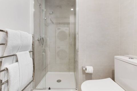 The bathroom has a glass shower, heated towel rail, vanity unit and toilet.