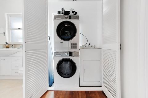 There is a washing machine, dryer, iron and ironing board in the laundry area.