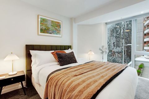 The Queen bed has warm tones with its orange throw and cushions.