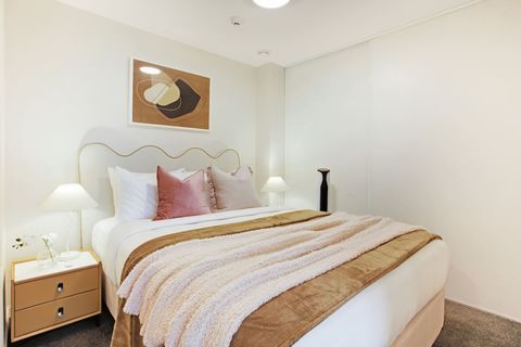 The Queen bed has warm tones with its neutral throw and cushions.