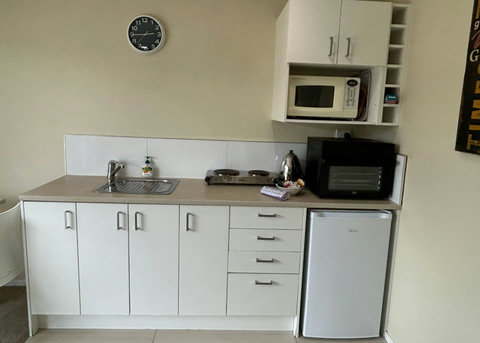 The kitchenette has a portable cooktop, bench oven, microwave, mini fridge and a larger fridge/freezer in the bathroom.