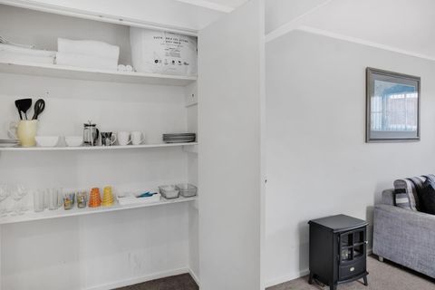 There are glasses, kitchen utensils and plates in the pantry cupboard.