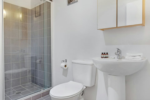 The bathroom has a shower, toilet, basin and storage cupboard.