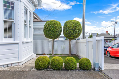 The round hedges match the era of the house perfectly.