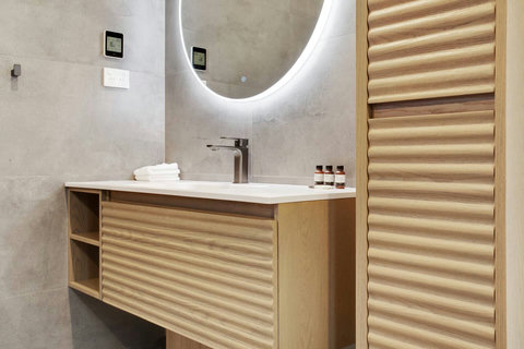 The ensuite bathroom has wooden features of the doors on the vanity and cupboard.