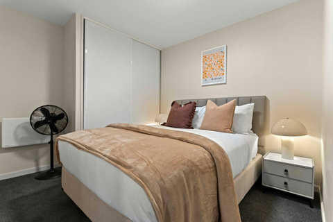 The Queen bed has neutral tones with its throw and cushions.