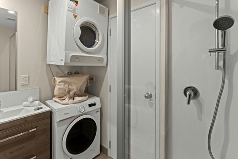 The washing machine and dryer are located in the main bathroom.