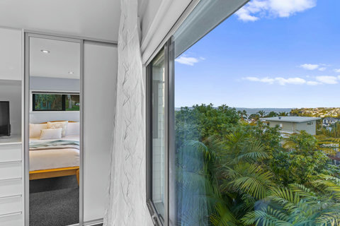 The view from your bedroom window overlooks greenery and sea in the far distance.