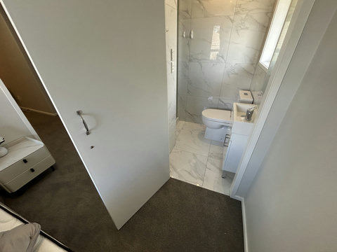 There is an ensuite bathroom in this Queen bedroom that has a shower, toilet and small vanity unit.