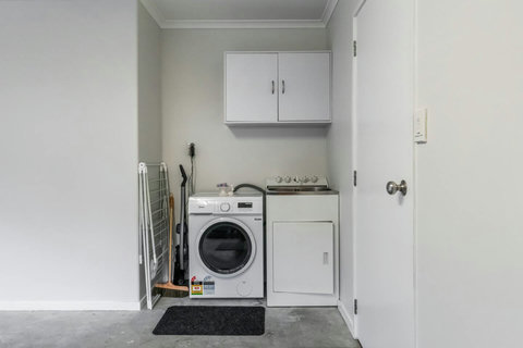 The washing machine is located in the garage and there is a drying frame for clothes.