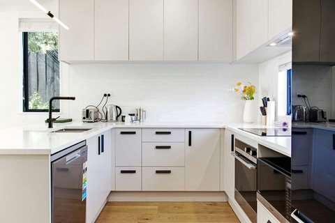 The kitchen is modern with its white and black colour scheme.