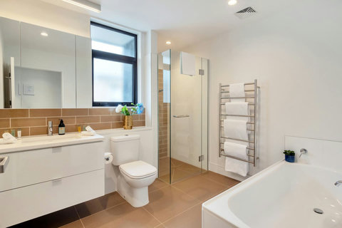 The large family bathroom has a separate shower, bathtub, toilet, large vanity, and heated towel rails.