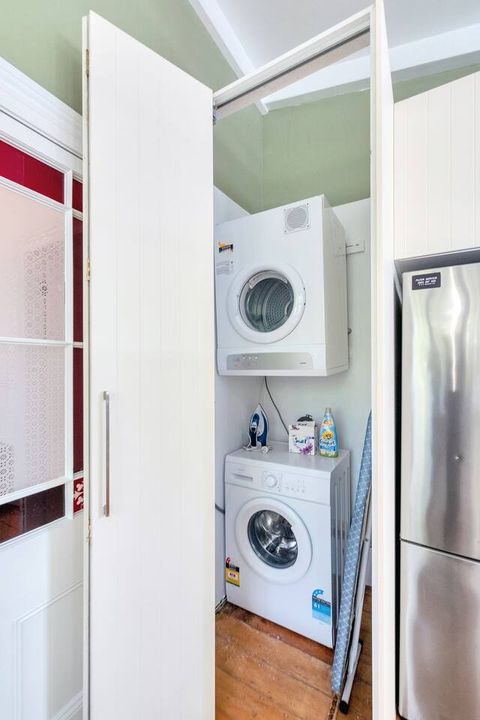 Separate full laundry includes a washing machine, dryer and ironing board.