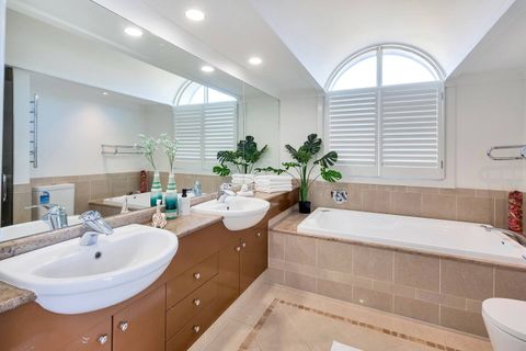 The blue suite ensuite bathroom has a built-in bath, twin sinks in the vanity and toilet and a heated towel rail.