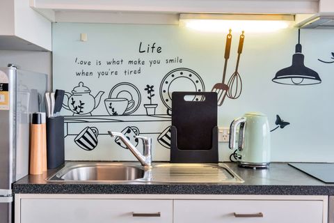 The backsplash has decorative artwork that adds to the overall apartment feel.