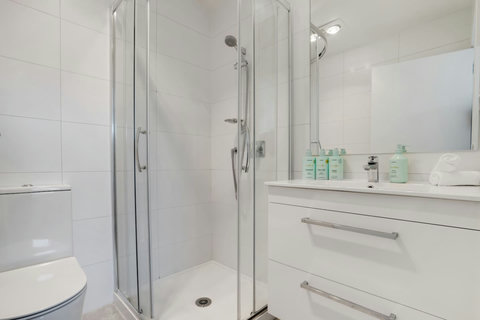 There is a toilet, glass shower box and vanity unit.