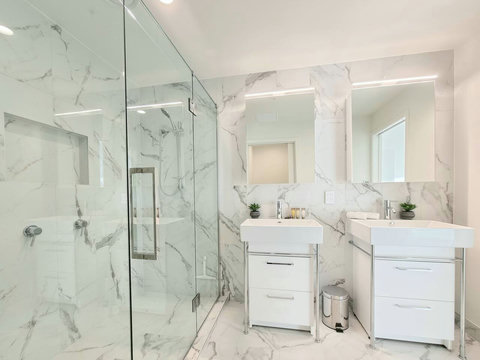 The ensuite bathroom has dual vanities, a glass shower and a toilet.