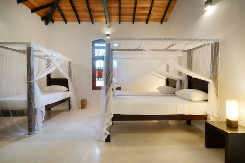 A spacious family room with three cosy canopy beds. Ideal for groups or families, this airy room features three comfortable beds with mosquito nets, warm lighting, and plenty of space. A baby cot can be added on request.