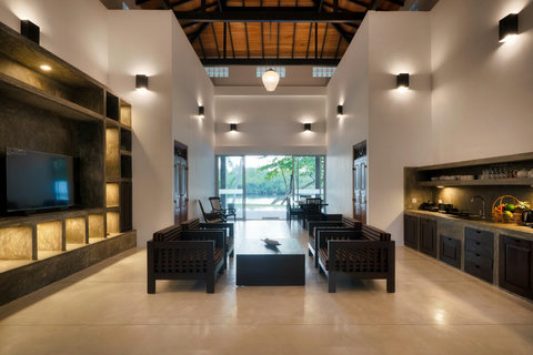 Full Living Room View- A spacious living area with high ceilings, warm lighting, and large glass doors that open to beautiful river views.