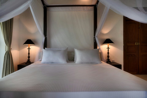 A cosy, elegant bedroom with a canopy bed.- Soft lighting, crisp white linens, and a classic four-poster design create a peaceful and relaxing space for restful nights.