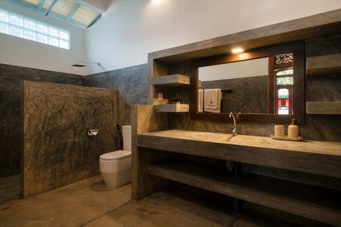 A modern rustic ensuite bathroom with a spacious open shower.
Polished cement finishes, warm lighting, and a large vanity create a stylish, comfortable space to refresh and unwind—right off your private bedroom.