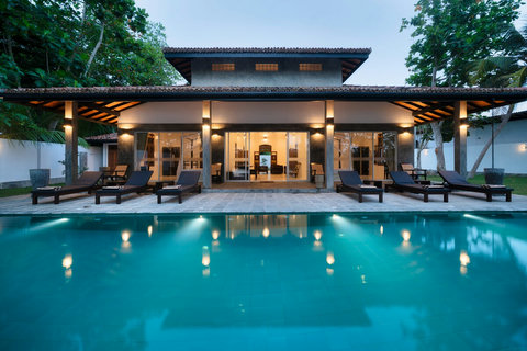 A stunning pool framed by the villa’s warm evening glow.
The pool reflects the soft lights of the villa, surrounded by loungers and greenery—a beautiful spot to unwind after a day of exploring.