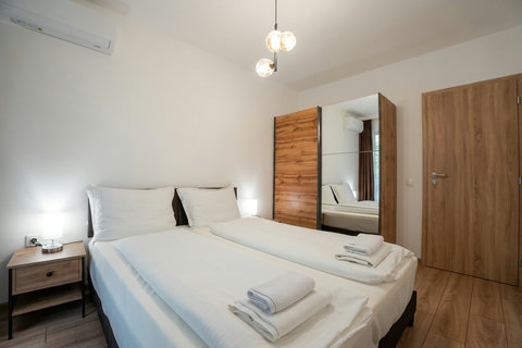 Bright minimalist bedroom with twin beds, AC, and mirrored wardrobe