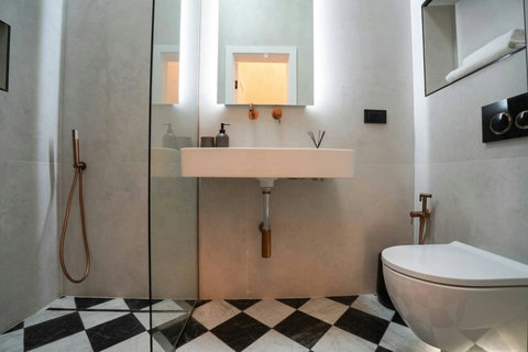 Designer bathroom with checkered floor, walk-in shower and rose gold fittings