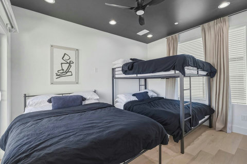 This stylish black-and-white bedroom features one queen bed and a queen bunk bed next to the rooftop, perfect for families or group. The modern decor creates a sleek, inviting space that is both comfortable and functional for a restful stay. 