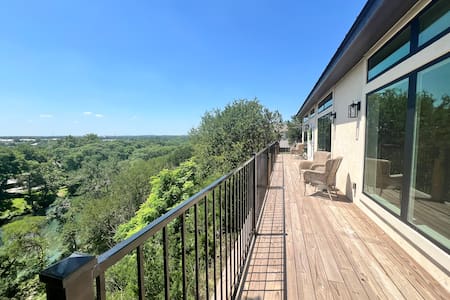Expansive treetop-view deck with seating and floor-to-ceiling windows