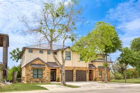 Modern stone-stucco duplex with garage, trees, and quiet setting