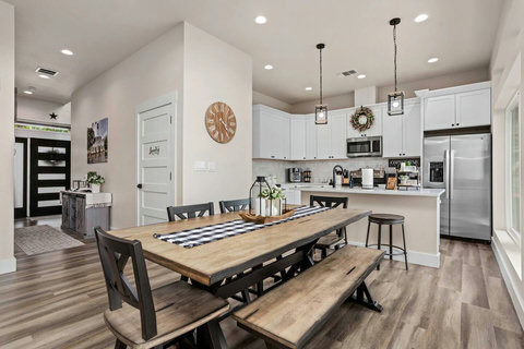 Gather in this open-concept kitchen and dining space with white cabinetry, modern appliances, and a large island for meal prep or dining. The well-lit dining table is perfect for enjoying meals.