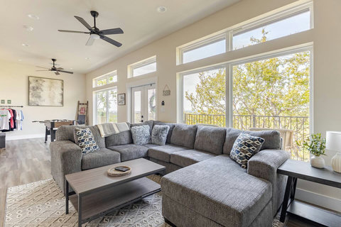 Relax in this spacious, sun-filled family room, featuring a large sectional sofa, cozy accent pillows, and floor-to-ceiling windows with stunning views. Room for everyone, the ideal spot to unwind after a day of exploring or gather for a movie night.