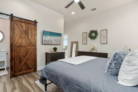 Serene bedroom with barn-door ensuite, TV, and modern decor
