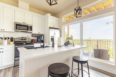 Gather in this open-concept kitchen and dining space with white cabinetry, modern appliances, and a large island for meal prep or dining. The well-lit dining table is perfect for enjoying meals.