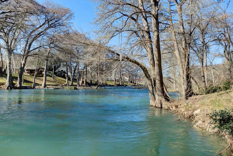 Tranquil riverfront under shady trees—ideal for tubing & kayaks