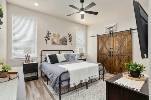 Chic farmhouse bedroom with barn doors, queen bed, ceiling fan & smart TV
