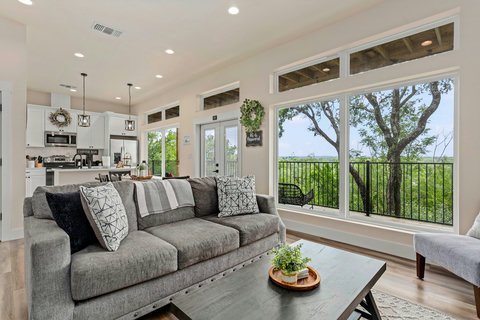 Light-filled open living, wall of windows, balcony & treetop views.