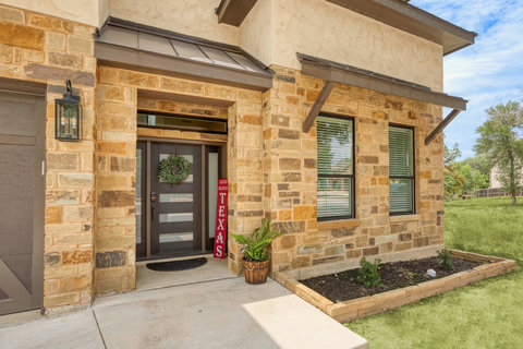 Inviting stone entry with modern door, metal awnings, and tidy landscaping