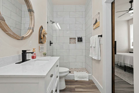 Stylish master bath with walk-in shower, quartz his and her vanities, and matte-black fixtures