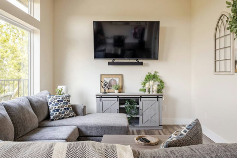 Spacious living area includes a cozy sectional sofa, an app streaming TV, and a game room with a foosball table. High ceilings and large windows with an epic view invite guests to relax and have fun.