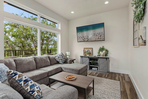 Bright lounge with big windows, plush sectional, smart TV & treetop views