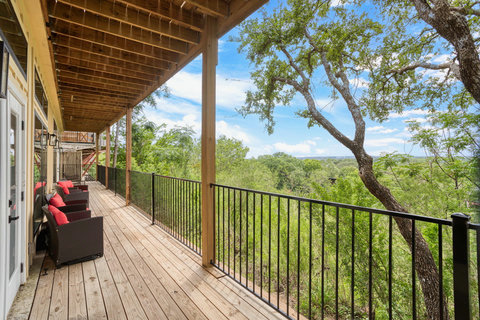 Spacious covered deck with seating and serene treetop views