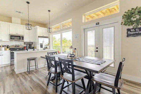 Dine in style at this chic table, flowing into a bright white kitchen with stainless steel appliances and a cozy rustic touch. Perfect for meals & mingling!
