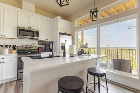 Cook and dine in this modern kitchen featuring white cabinetry, stainless steel appliances, and an island with bar seating for two. A charming coffee bar makes it perfect for your morning caffeine boost.