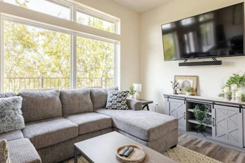 Spacious living area includes a cozy sectional sofa, an app streaming TV, and a game room with a foosball table. High ceilings and large windows with an epic view invite guests to relax and have fun.