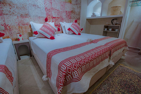 Beds with red Moroccan throws and arched shelves / Lits aux plaids marocains rouges et étagères en arc