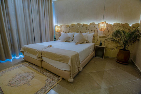 Double bed with stone wall and plant / Lit double, mur en pierre et plante