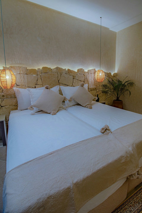Double bed under the lit stone wall / Lit double sous le mur en pierre éclairé