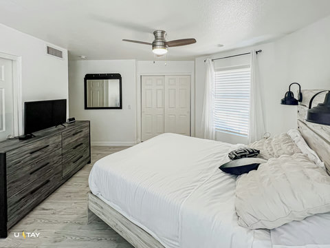 Bright king suite with TV, fan, closet and cozy modern decor